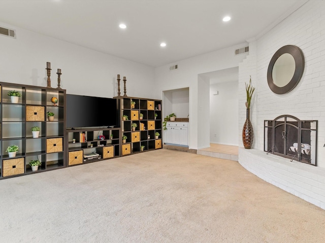 living area featuring visible vents, a brick fireplace, and carpet floors