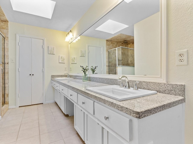 full bathroom featuring a sink, a stall shower, a skylight, and tile patterned floors