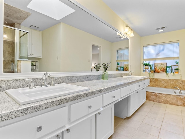 bathroom with a sink, a skylight, a shower stall, and tile patterned floors