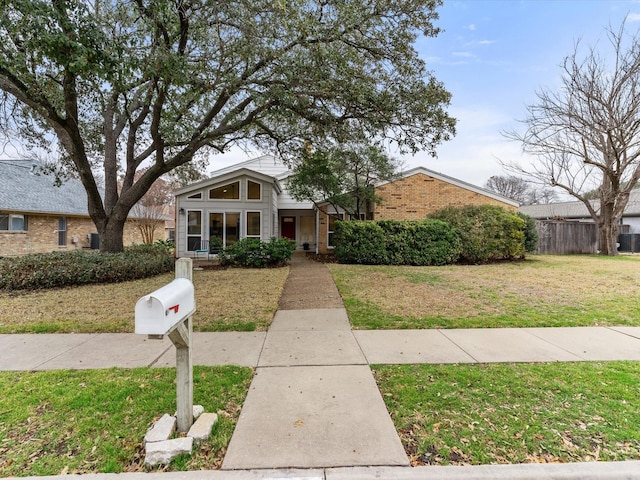 mid-century home featuring brick siding, a front lawn, and fence