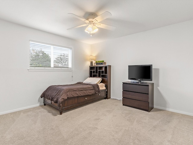 bedroom featuring light carpet, a ceiling fan, and baseboards