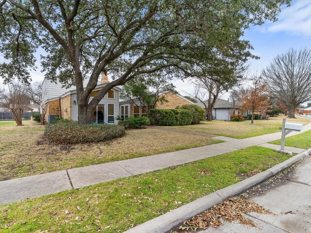 exterior space with brick siding and a front yard