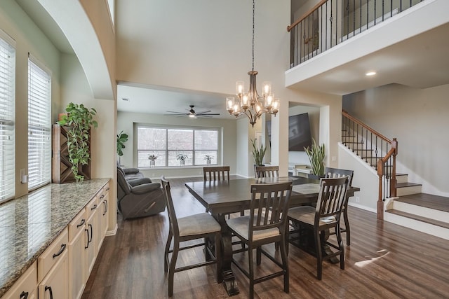 dining area featuring dark wood finished floors, baseboards, stairs, and a high ceiling