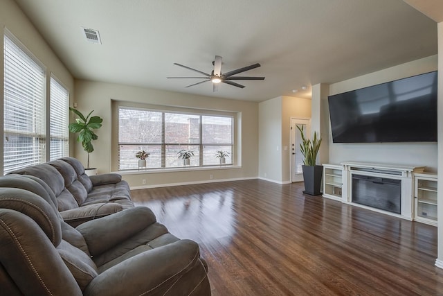 living room featuring a glass covered fireplace, a wealth of natural light, visible vents, and dark wood-style flooring