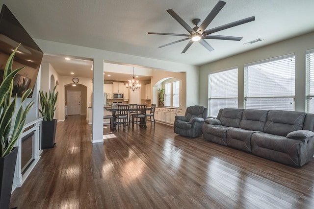 living room with dark wood finished floors, visible vents, arched walkways, and a notable chandelier