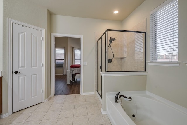 ensuite bathroom featuring tile patterned flooring, a garden tub, plenty of natural light, and a stall shower