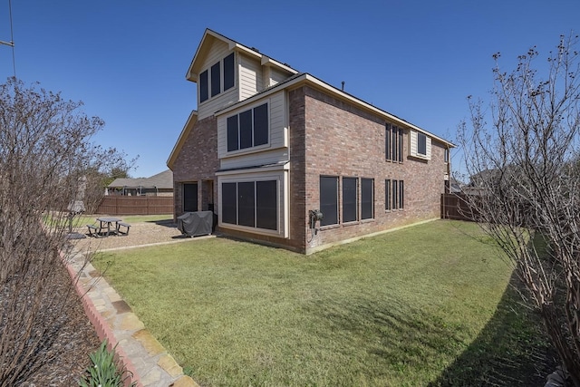 rear view of property featuring a patio area, a fenced backyard, brick siding, and a lawn