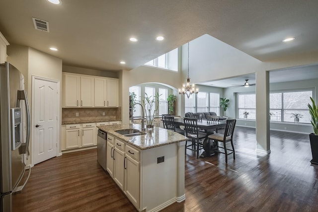 kitchen featuring visible vents, open floor plan, light stone counters, appliances with stainless steel finishes, and a sink