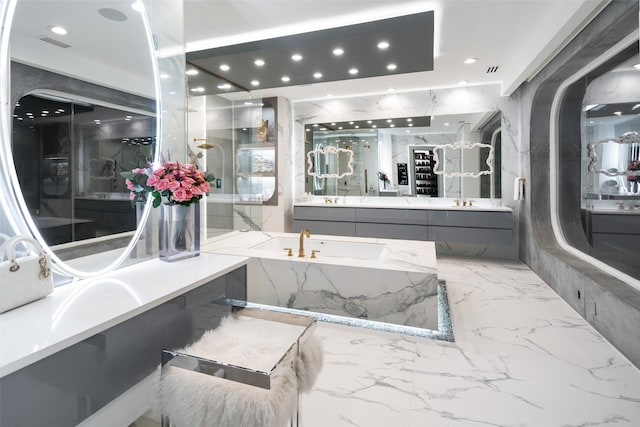 full bathroom with visible vents, a garden tub, stone wall, marble finish floor, and vanity