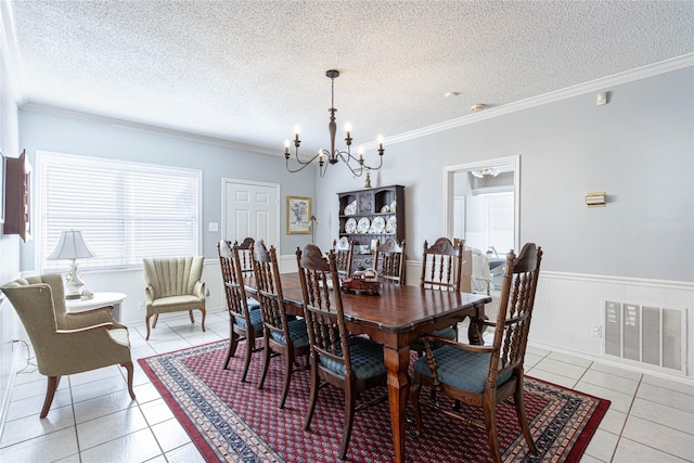 dining room featuring visible vents, light tile patterned floors, wainscoting, an inviting chandelier, and a textured ceiling