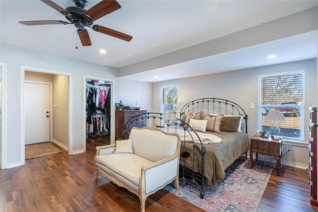 bedroom featuring wood finished floors, baseboards, recessed lighting, ceiling fan, and a walk in closet