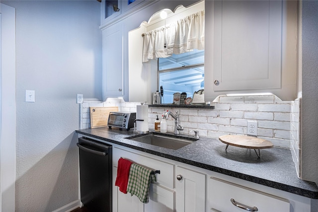 kitchen featuring tasteful backsplash, a toaster, dishwasher, white cabinetry, and a sink