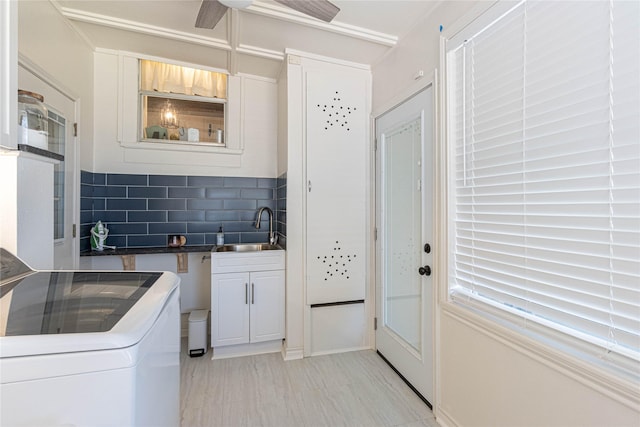 kitchen with tasteful backsplash, glass insert cabinets, washer / clothes dryer, white cabinetry, and a sink