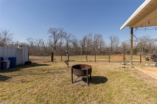 view of yard featuring a rural view, an outdoor fire pit, and fence