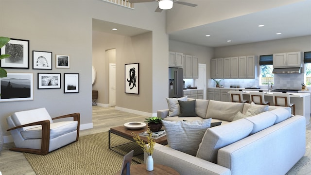 living area featuring light wood finished floors, recessed lighting, a ceiling fan, and baseboards