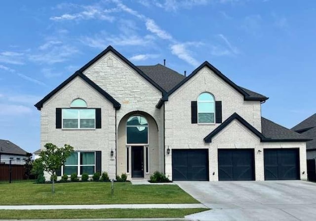 french provincial home featuring a shingled roof, fence, concrete driveway, a front yard, and an attached garage