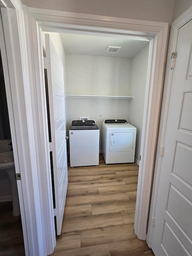 laundry area featuring visible vents, wood finished floors, laundry area, and washing machine and clothes dryer