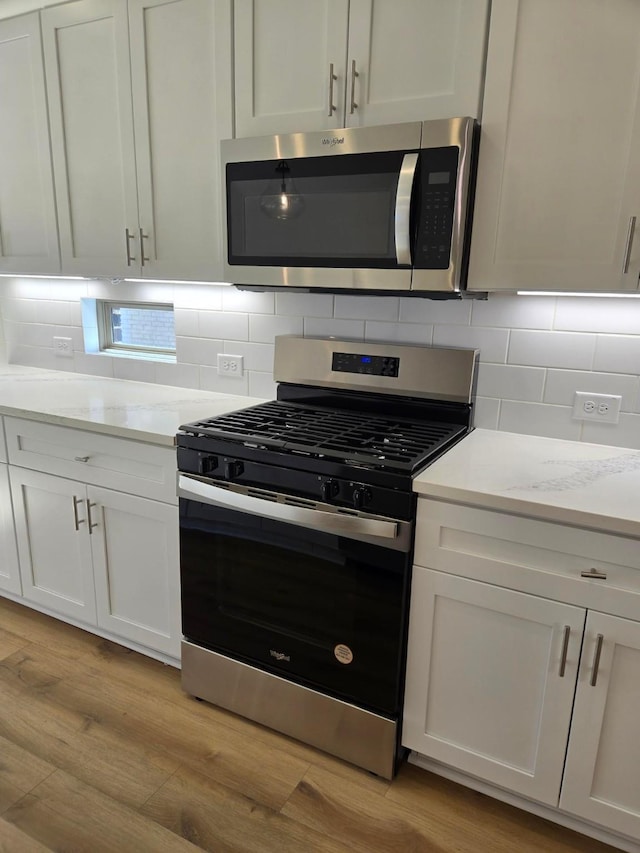 kitchen featuring light wood-style flooring, backsplash, and appliances with stainless steel finishes