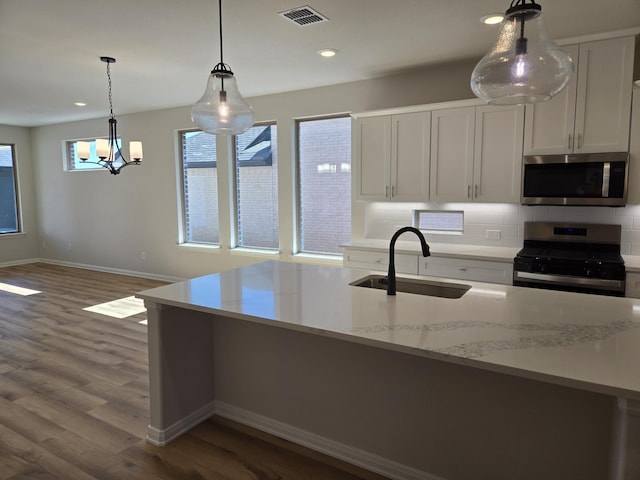 kitchen with visible vents, dark wood-type flooring, a sink, tasteful backsplash, and stainless steel appliances