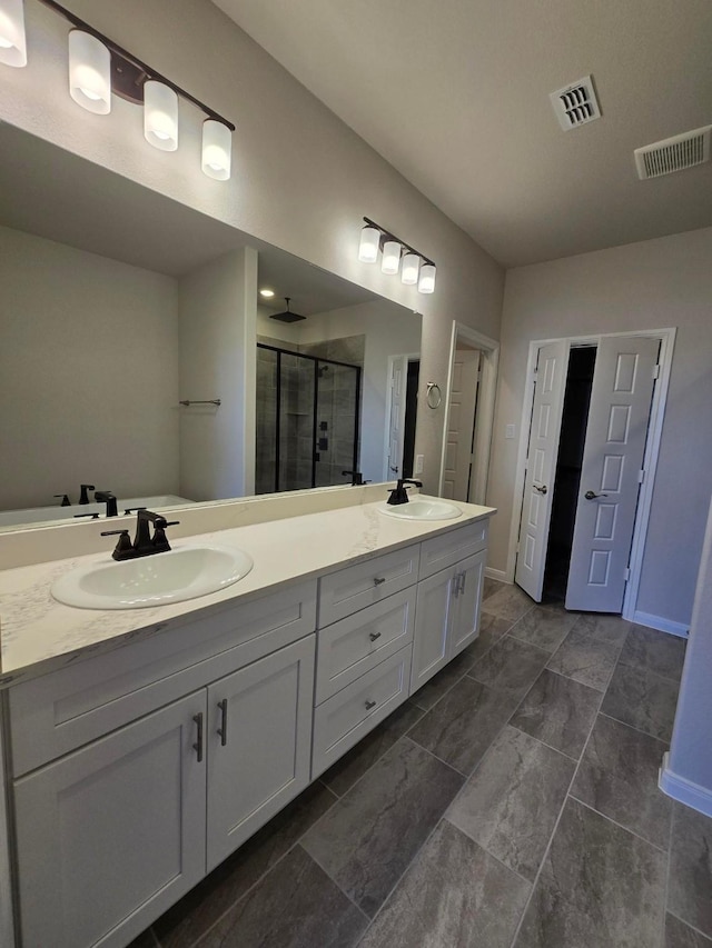 full bath featuring double vanity, visible vents, a shower stall, and a sink