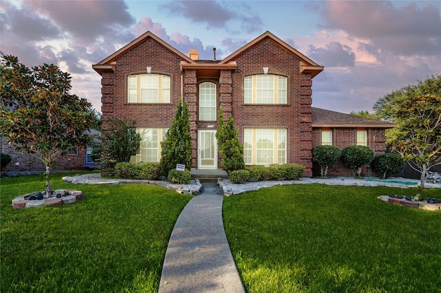 view of front of home with a front lawn, brick siding, roof with shingles, and a chimney