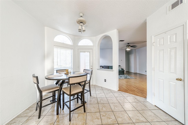 dining area featuring ceiling fan, light tile patterned floors, visible vents, and a textured ceiling