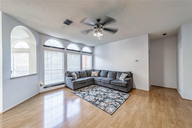 living area with visible vents, a textured ceiling, wood finished floors, and a ceiling fan