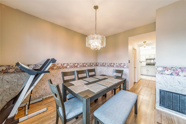 dining room with light wood-style flooring, visible vents, a chandelier, and wainscoting