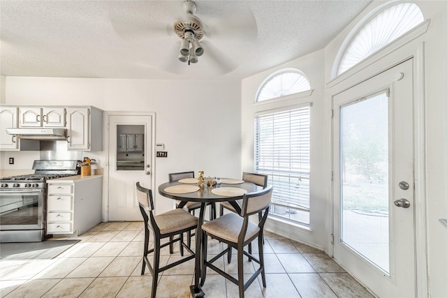 dining space featuring light tile patterned floors, a textured ceiling, and ceiling fan