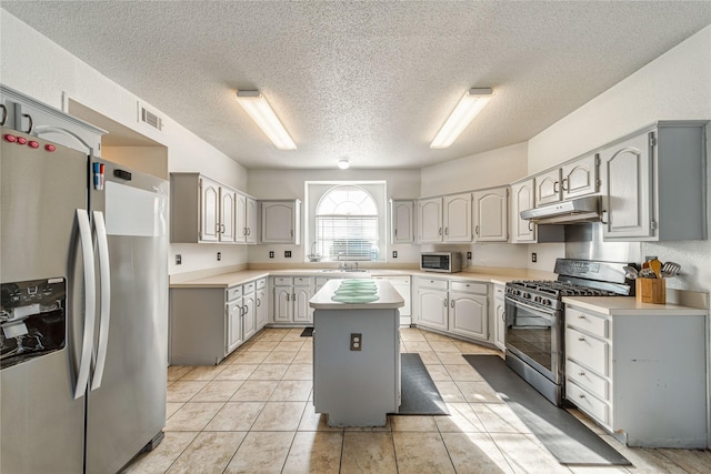 kitchen with gray cabinets, under cabinet range hood, a sink, a kitchen island, and appliances with stainless steel finishes