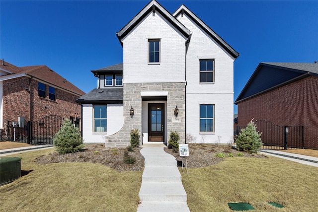 view of front of property featuring brick siding, a gate, fence, and stone siding