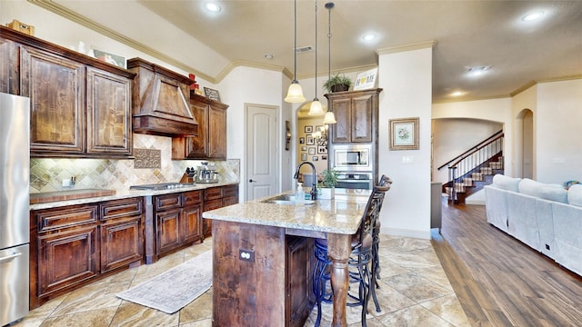 kitchen with a kitchen bar, a sink, light stone counters, tasteful backsplash, and stainless steel appliances