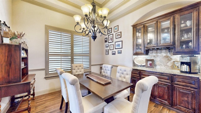 dining room with a dry bar, crown molding, a tray ceiling, and wood finished floors