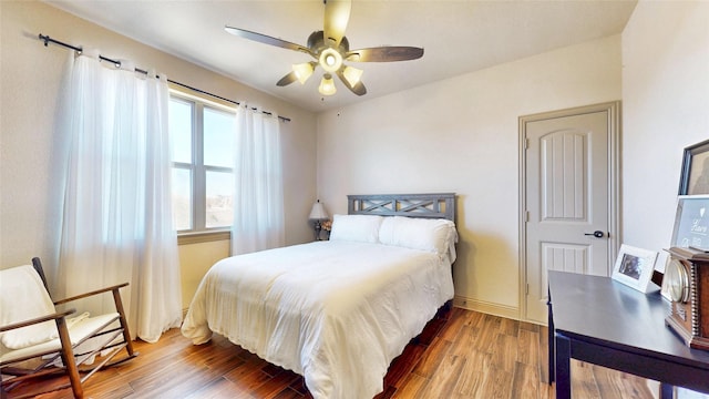 bedroom featuring ceiling fan, baseboards, and wood finished floors