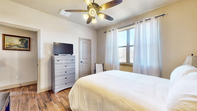 bedroom with visible vents, wood finished floors, baseboards, and ceiling fan