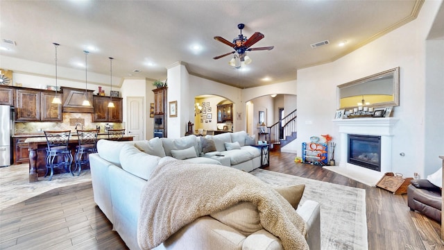 living room featuring arched walkways, visible vents, wood finished floors, and a glass covered fireplace