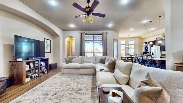 living room with ceiling fan, arched walkways, wood finished floors, and crown molding