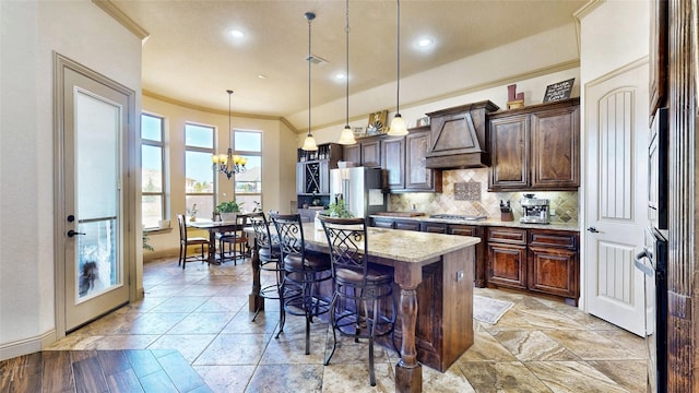 kitchen with custom exhaust hood, decorative backsplash, appliances with stainless steel finishes, crown molding, and a kitchen breakfast bar