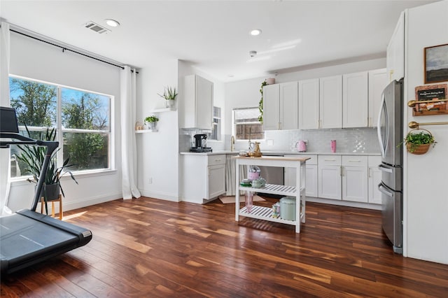 kitchen featuring visible vents, backsplash, dark wood finished floors, and light countertops