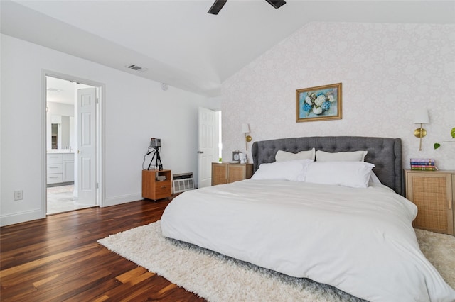 bedroom with wood finished floors, visible vents, baseboards, wallpapered walls, and vaulted ceiling