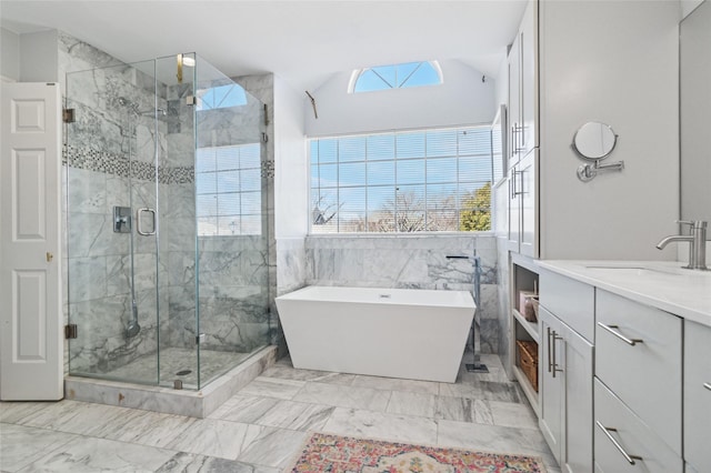 full bath with vanity, lofted ceiling, a stall shower, a freestanding bath, and marble finish floor