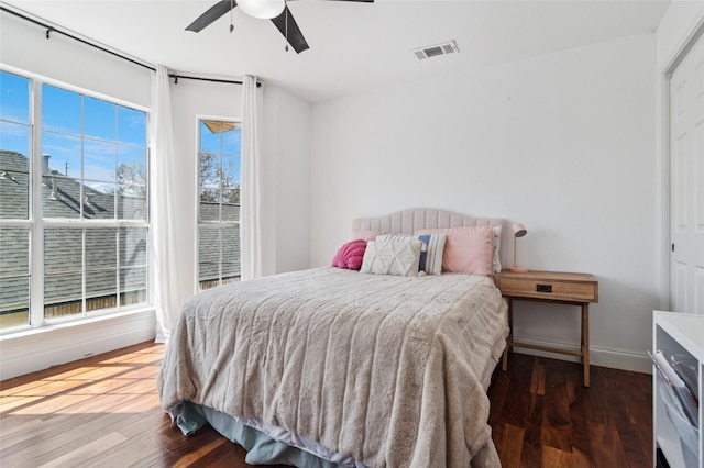 bedroom featuring ceiling fan, visible vents, baseboards, and wood finished floors