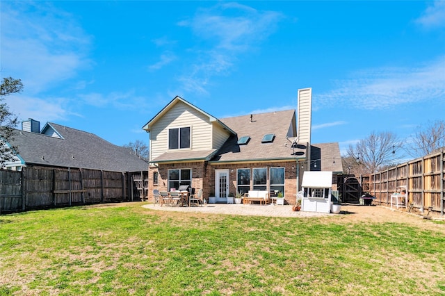 rear view of property featuring a patio, a fenced backyard, a yard, brick siding, and a chimney