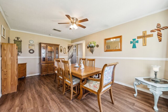 dining area with visible vents, ornamental molding, a ceiling fan, wood finished floors, and wainscoting