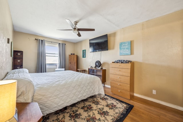 bedroom featuring ceiling fan, baseboards, and wood finished floors