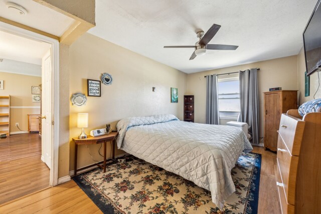 bedroom featuring light wood finished floors, ceiling fan, and baseboards