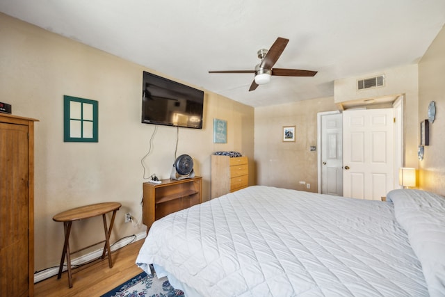 bedroom featuring visible vents, baseboards, ceiling fan, and wood finished floors