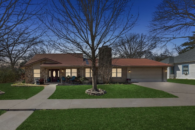 view of front of property featuring a tile roof, a front yard, a chimney, a garage, and driveway