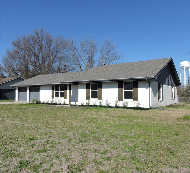 ranch-style house with a front lawn, an attached garage, and a shingled roof