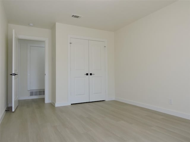 unfurnished bedroom with light wood finished floors, visible vents, a closet, and baseboards